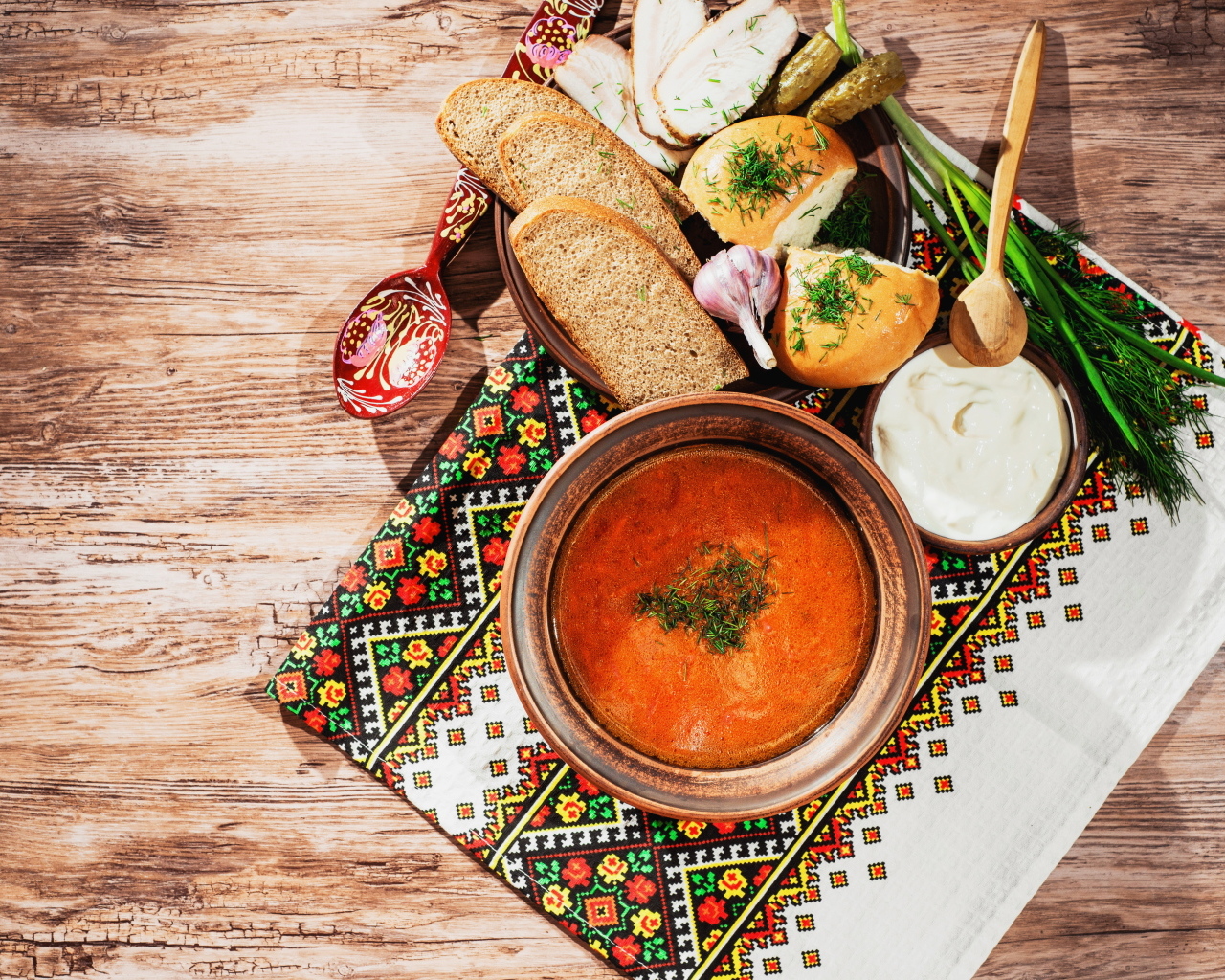 Тарелка борща на столе с салом, хлебом и зеленью