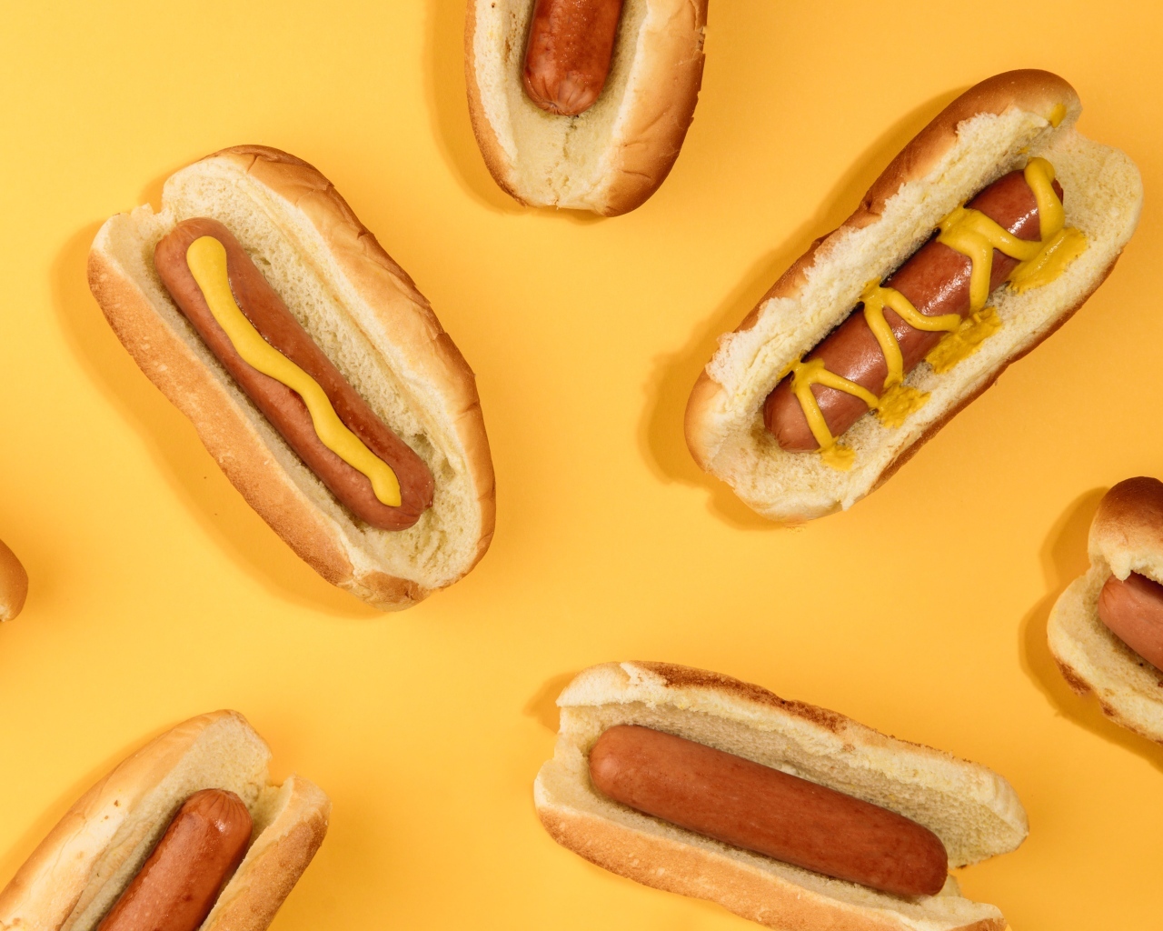 Аппетитные хот доги на желтом столе
