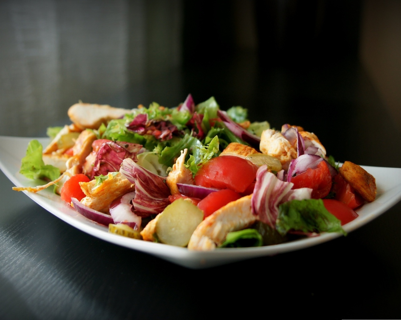 Аппетитный салат в белой тарелке на черном фоне