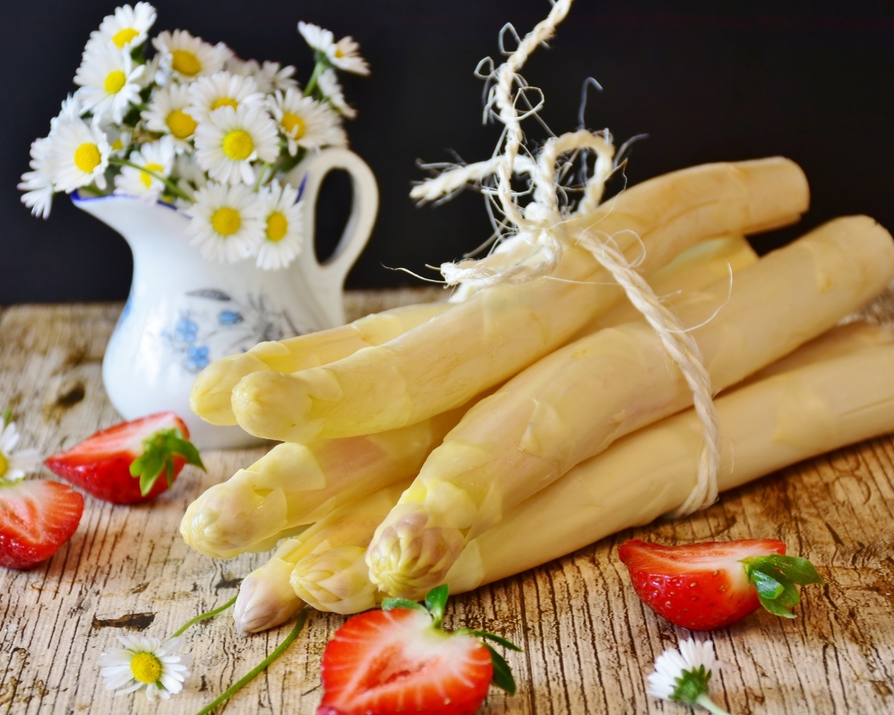 Спаржа на столе с ромашками и ягодами клубники