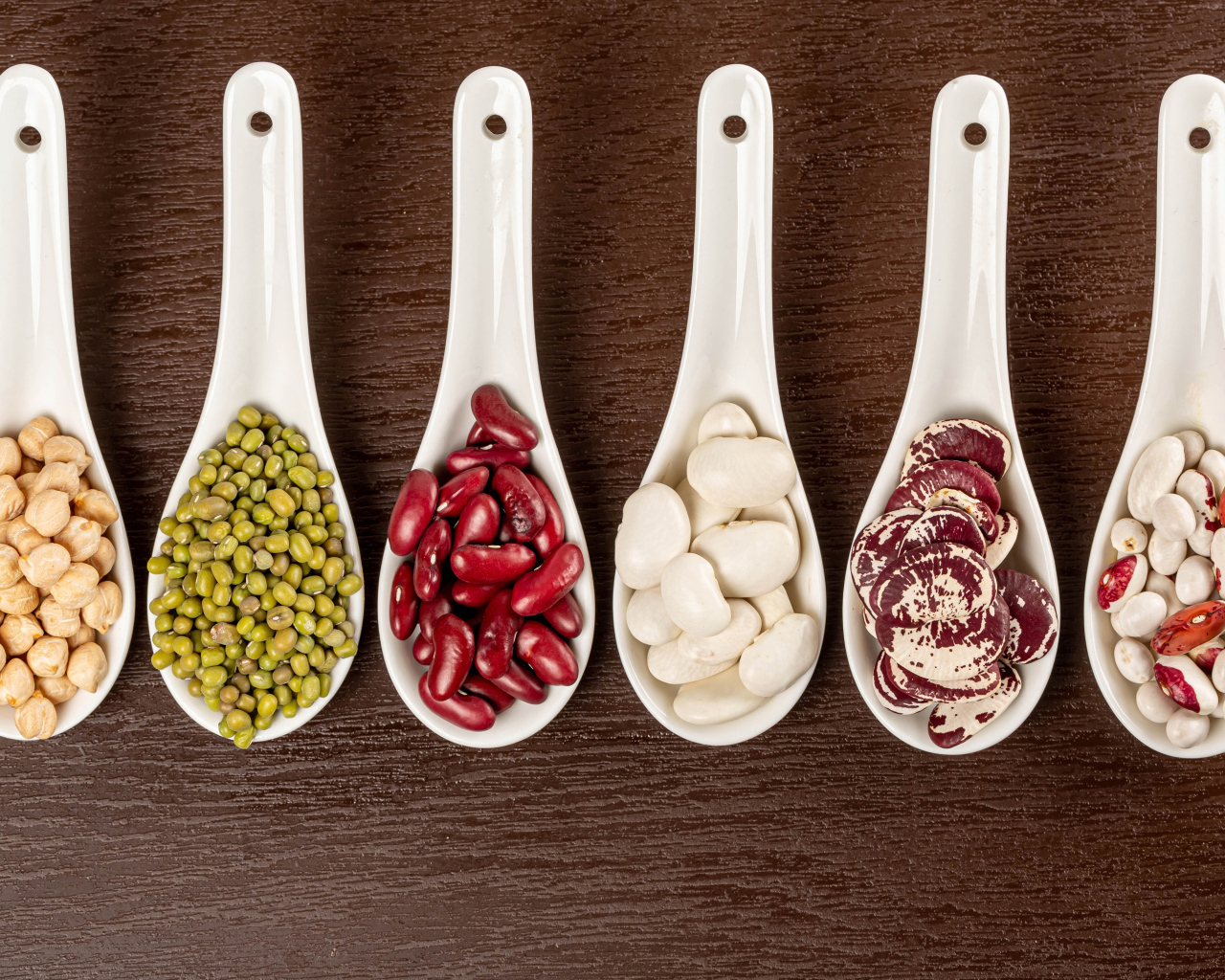 Бобовые зерна в белых ложках на столе