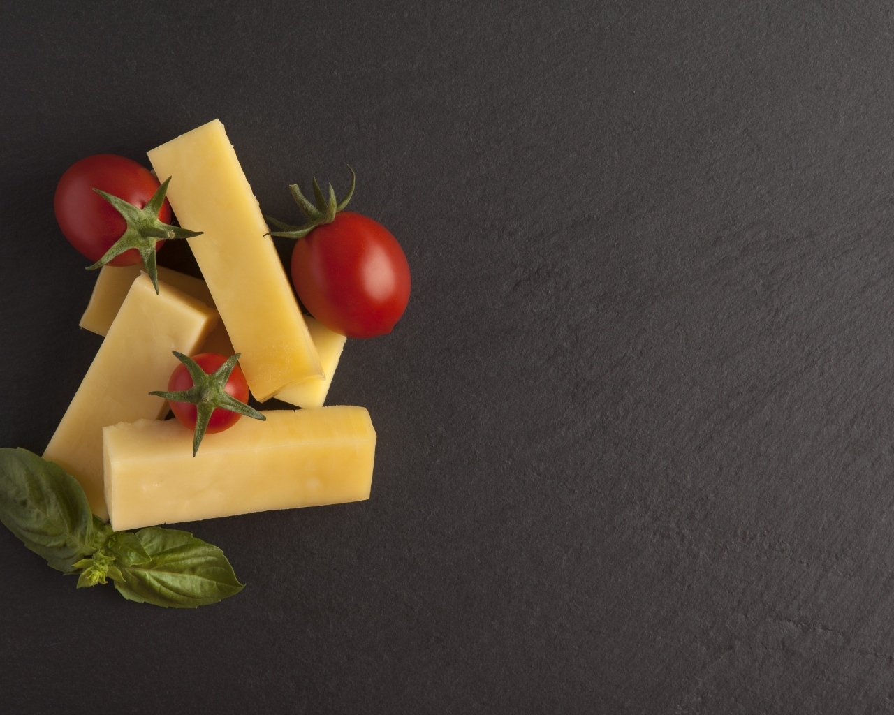 Сыр с помидорами и листьями базилика на сером столе