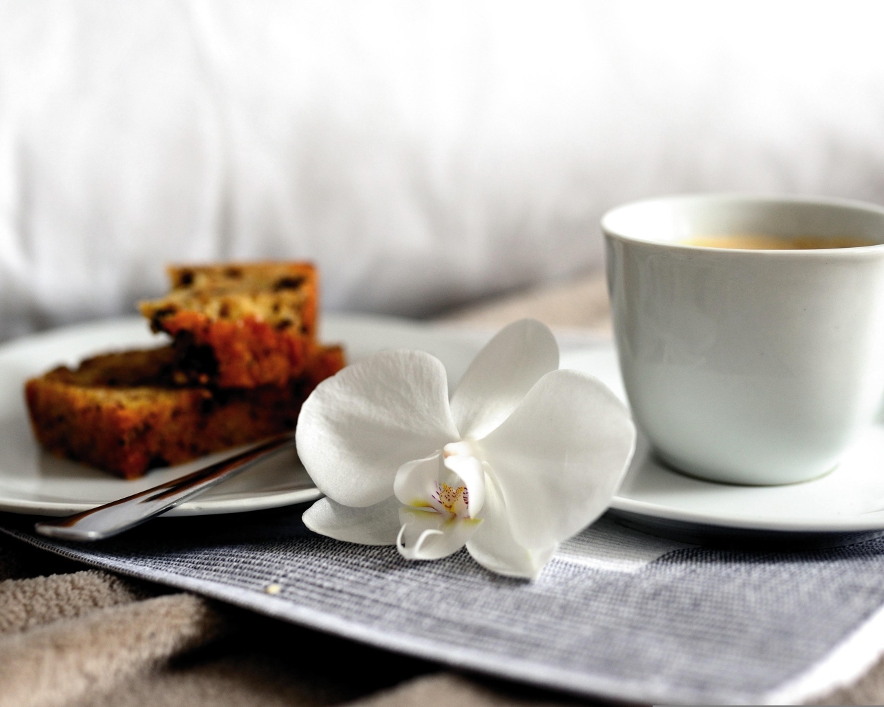 Чашка кофе с цветком орхидеи и куском кекса