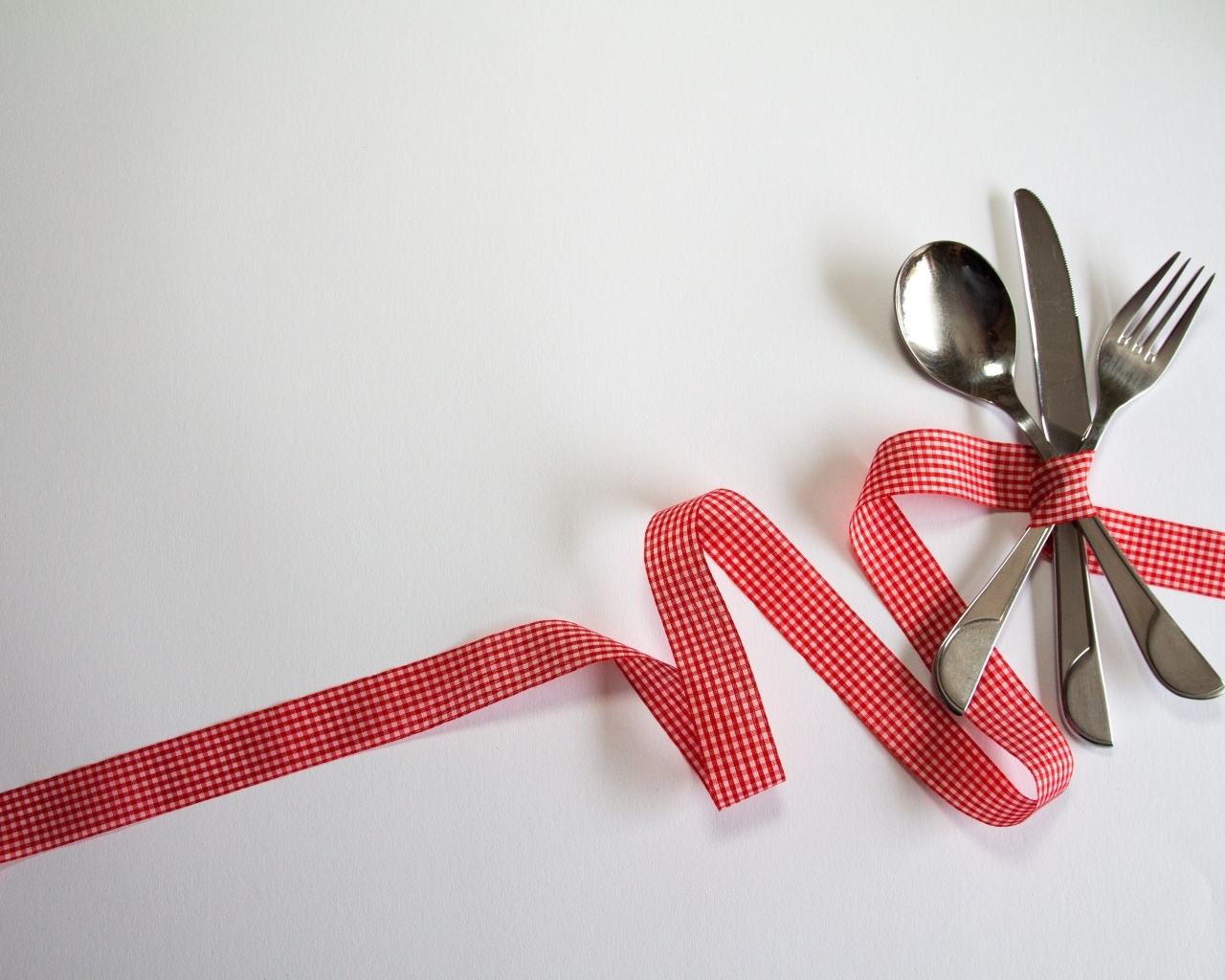 Столовые приборы перевязаны лентой на сером фоне