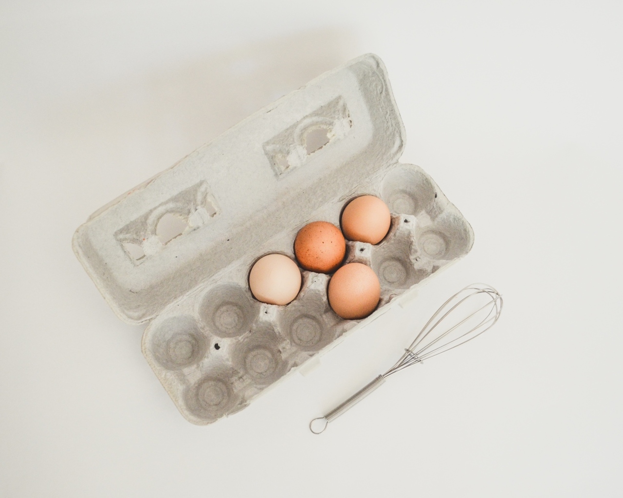 Четыре яйца в лотке на сером фоне