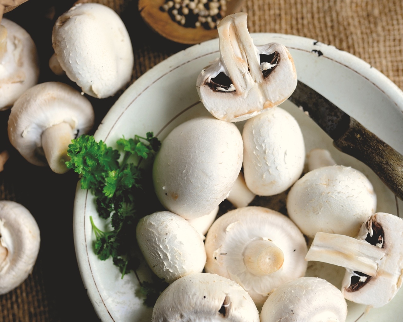 Свежие шампиньоны на тарелке на столе