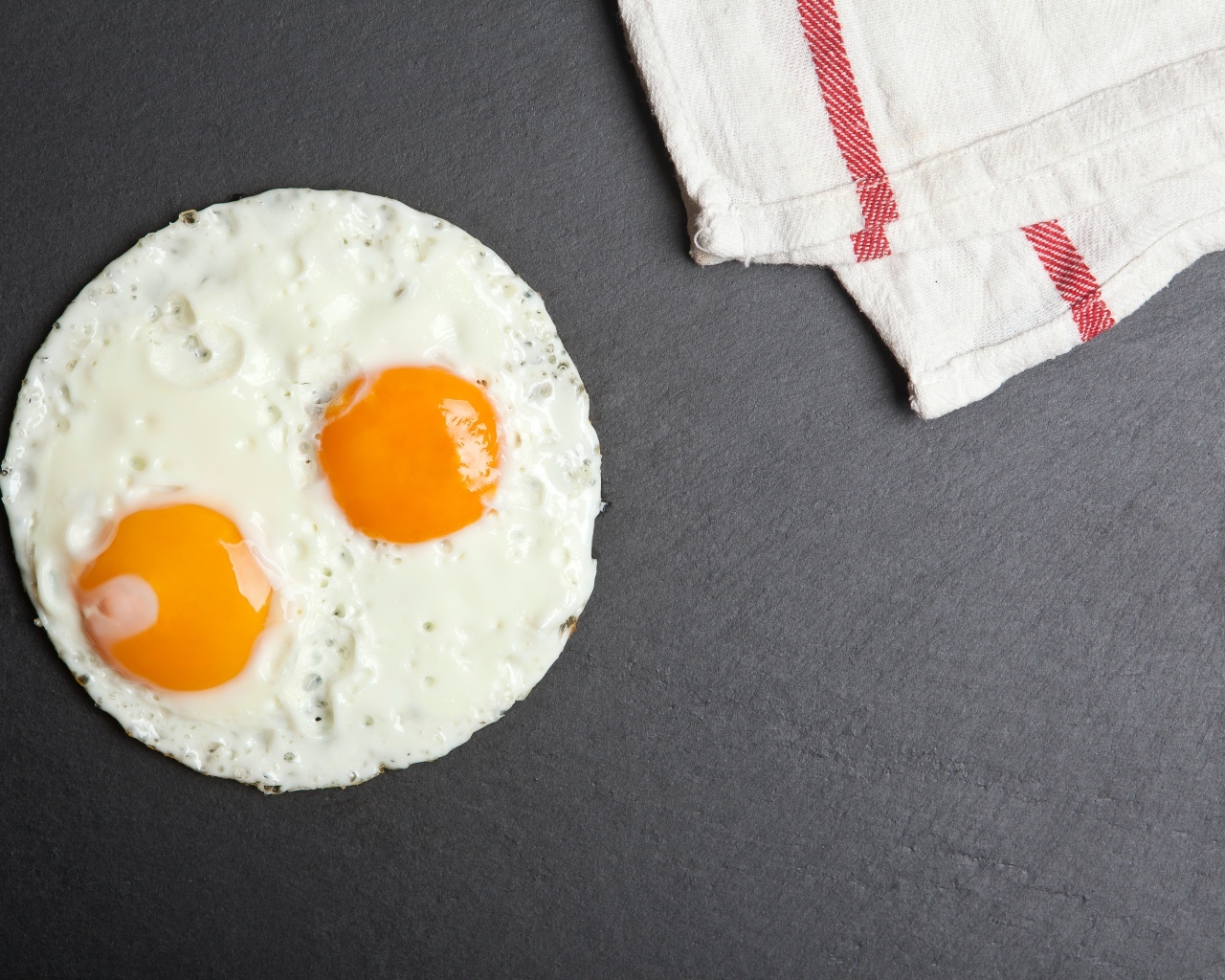 Яичница глазунья на сером столе с полотенцем