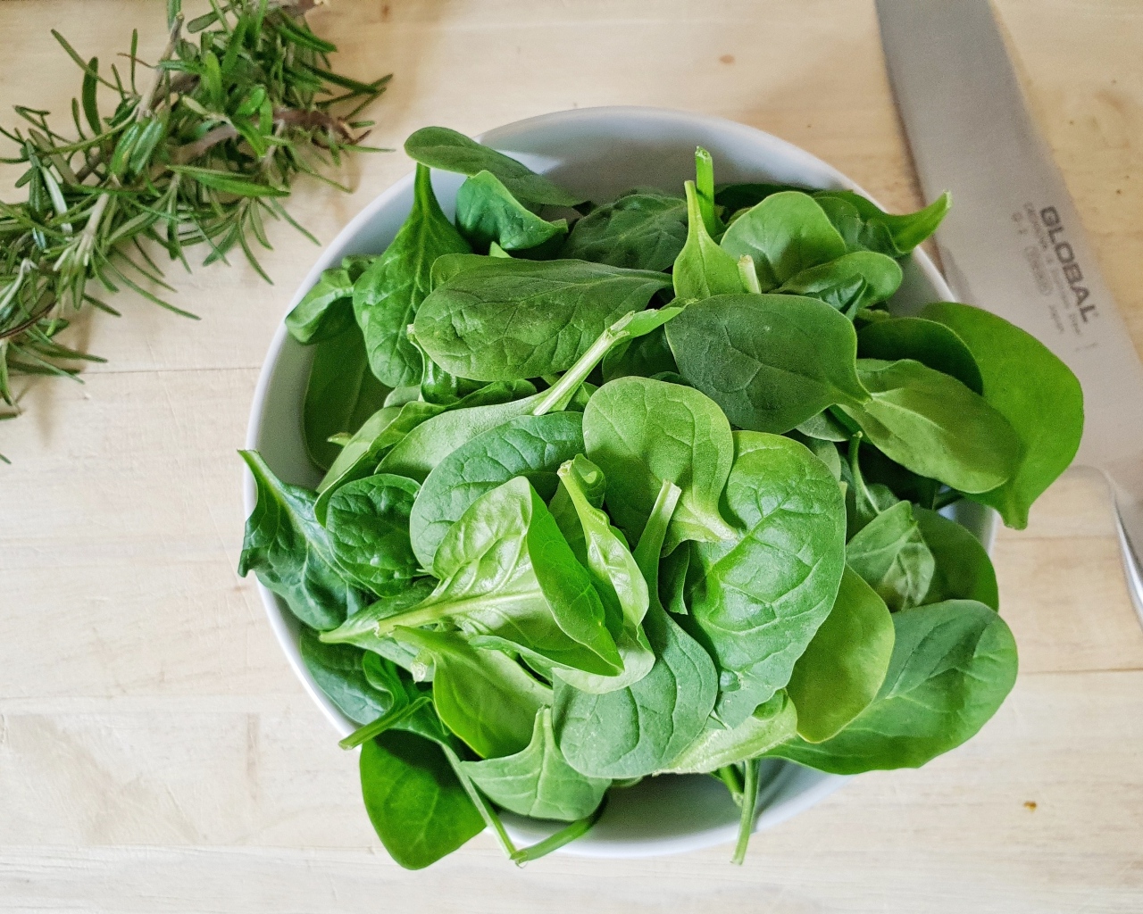 Зеленые листья базилика на столе с розмарином