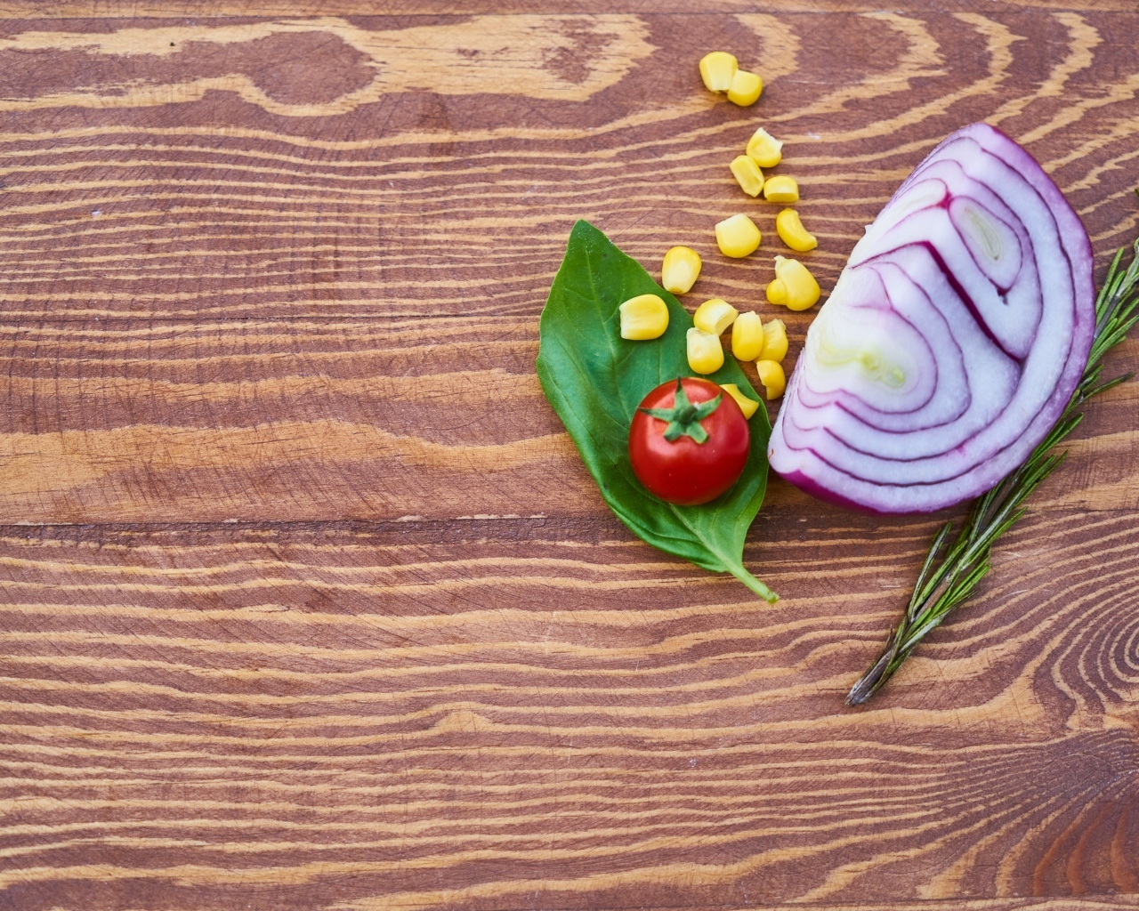 Половина лука на столе с кукурузой и помидором