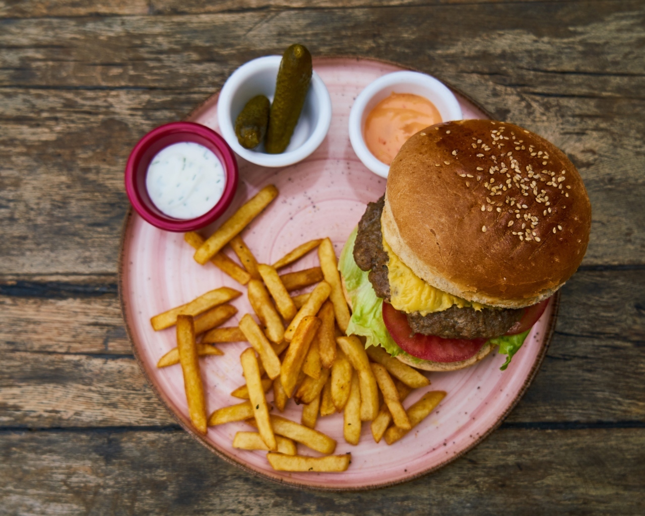 Гамбургер на тарелке с картофелем фри, огурцами и соусом