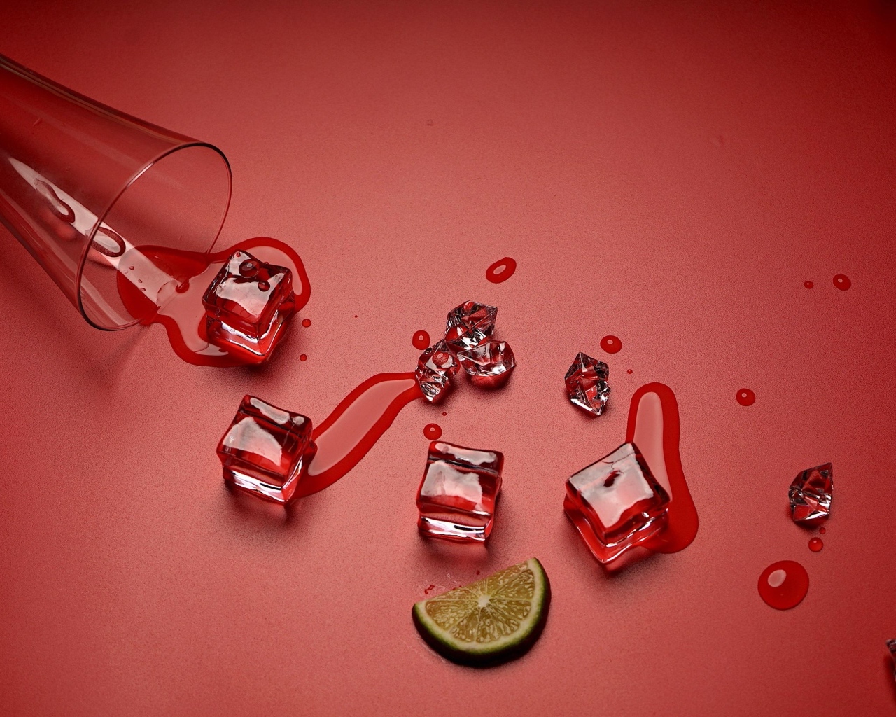 Кубики льда на красном фоне с кусочком лайма и стаканом