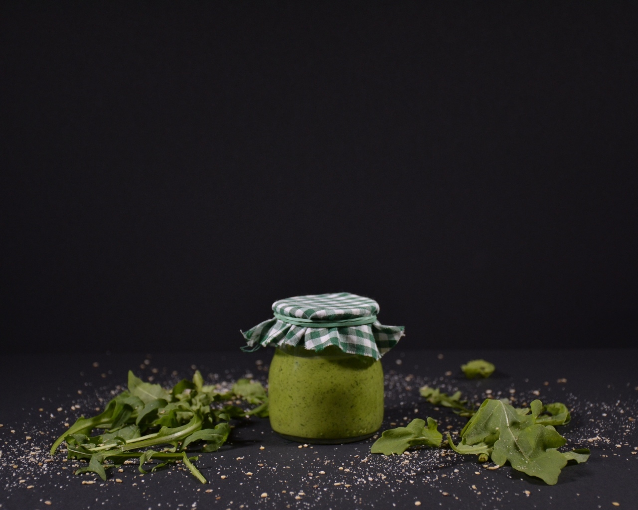 Банка соуса песто на черном фоне