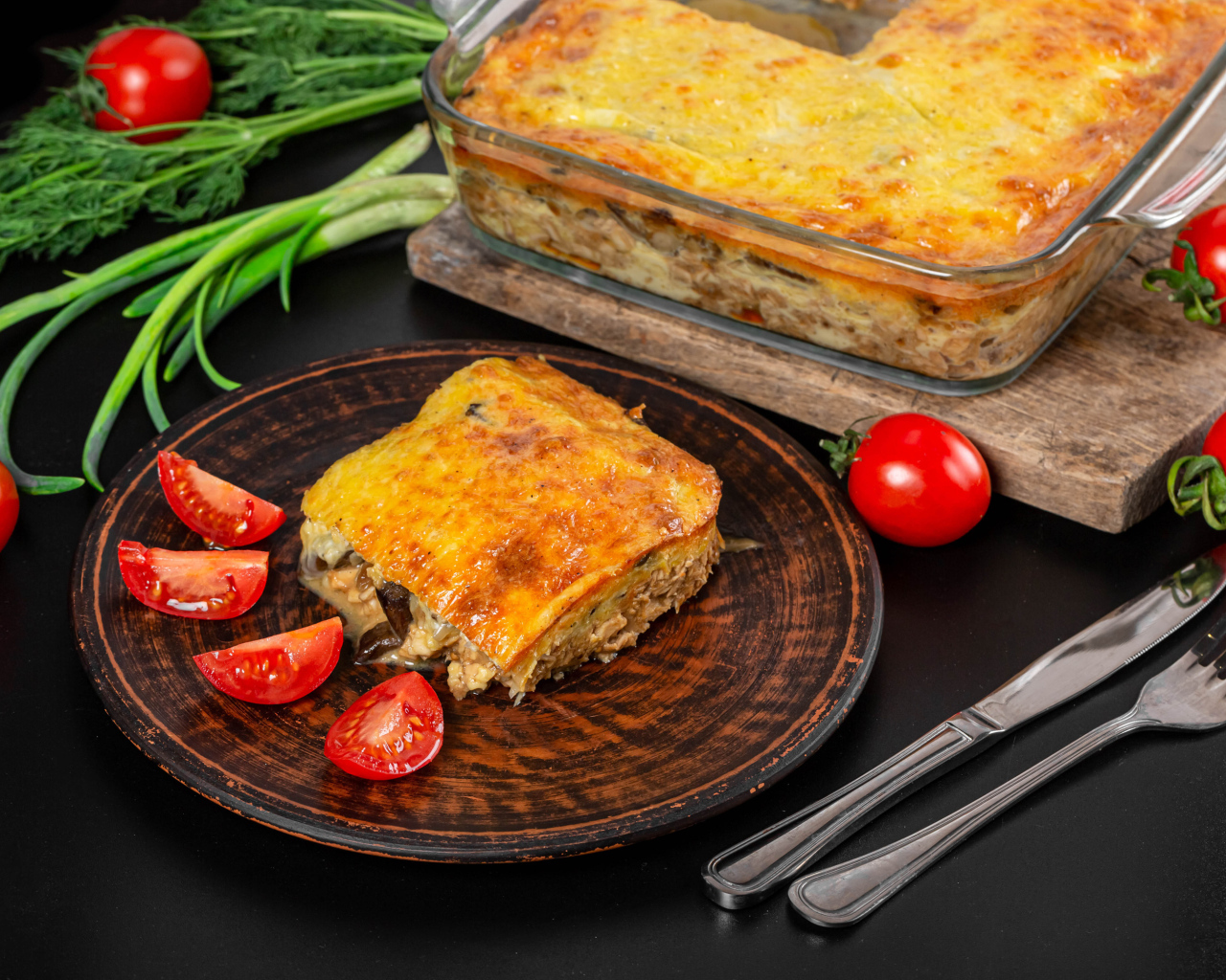 Лазанья на тарелке с помидорами и зеленью