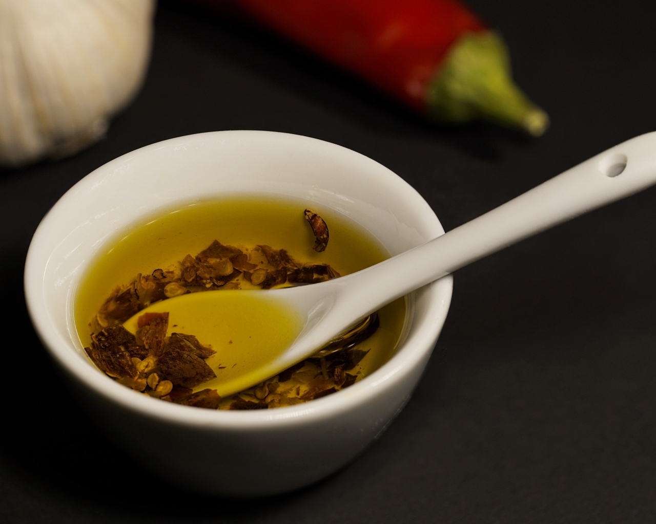 Оливковое масло в тарелке на столе с перцем и чесноком