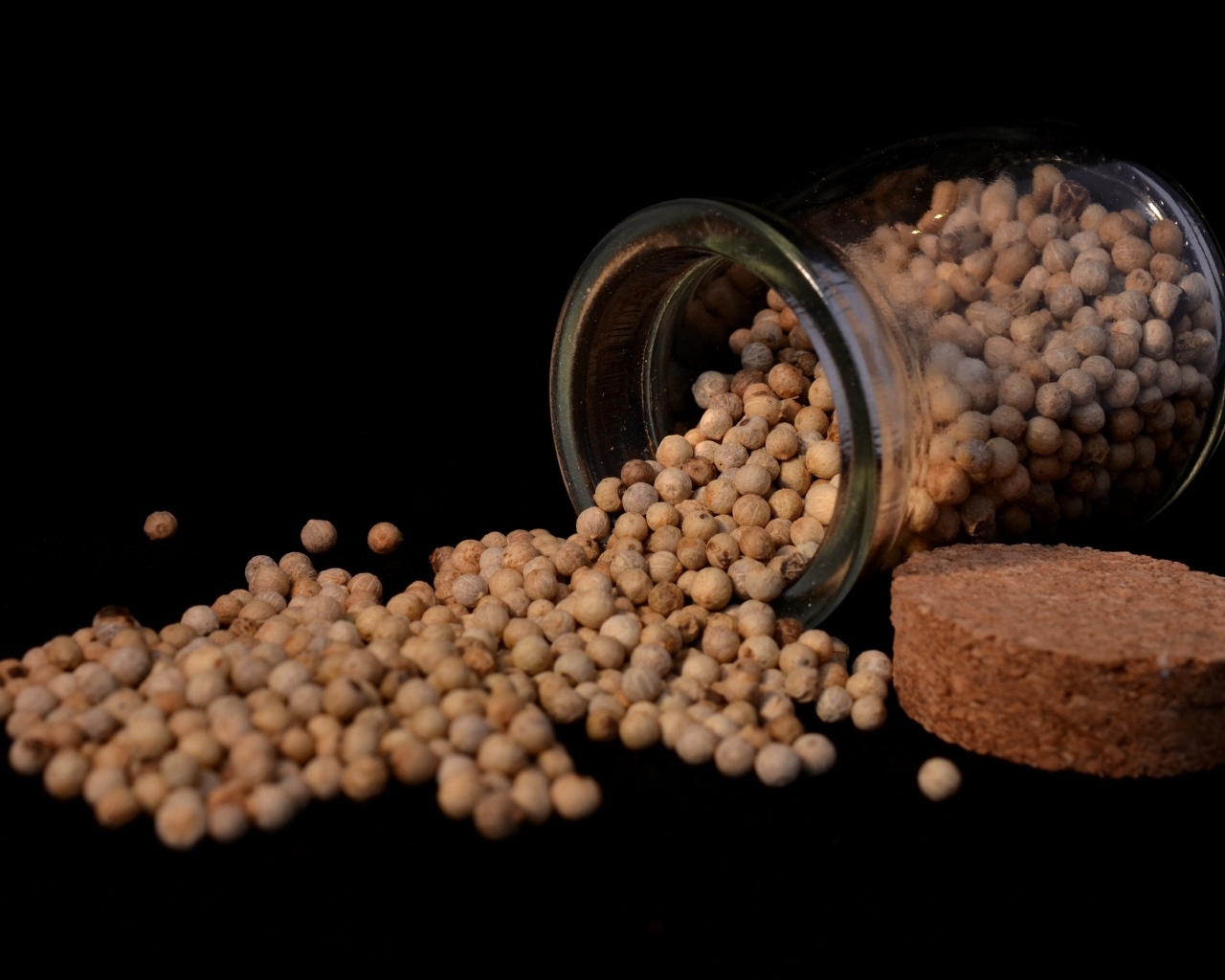 Перец горошком в банке на черном фоне