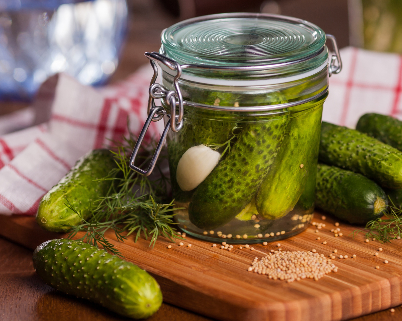 Маринованные огурцы в банке на столе со свежими