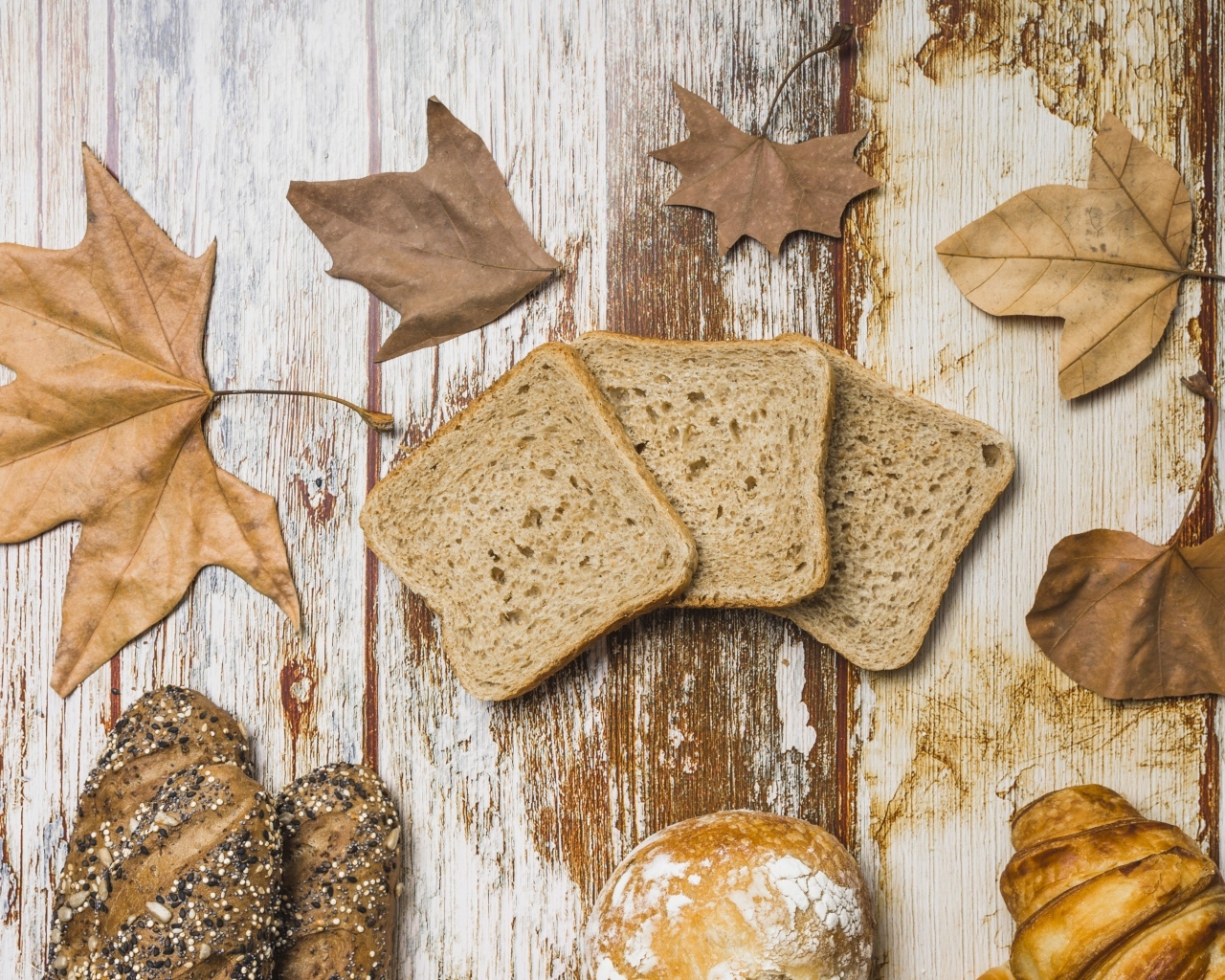 Куски хлеба с листьями на деревянном столе