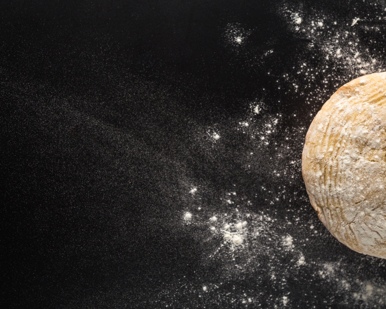 Сырое тесто на черном столе с мукой