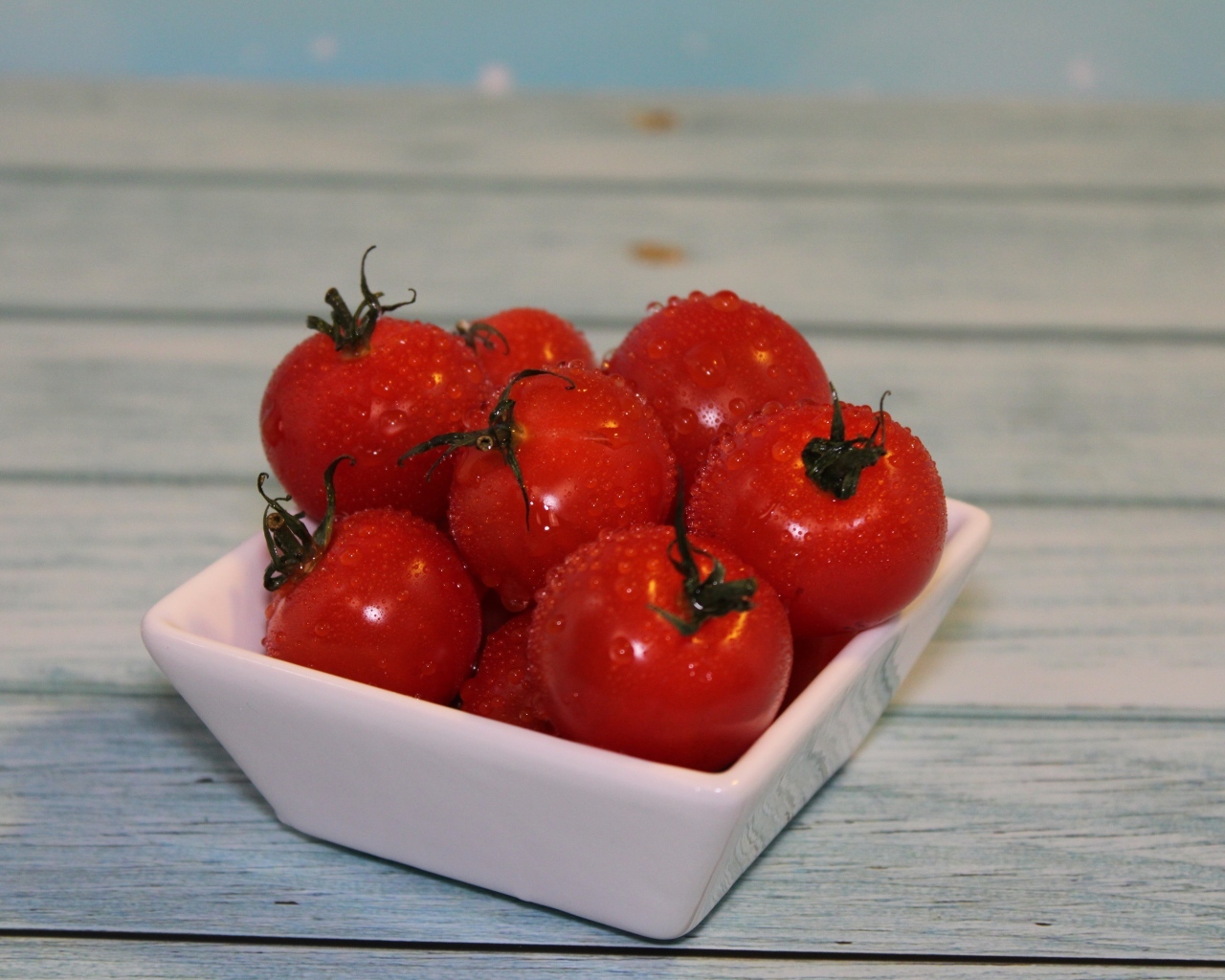 Красные мокрые помидоры в белой тарелке