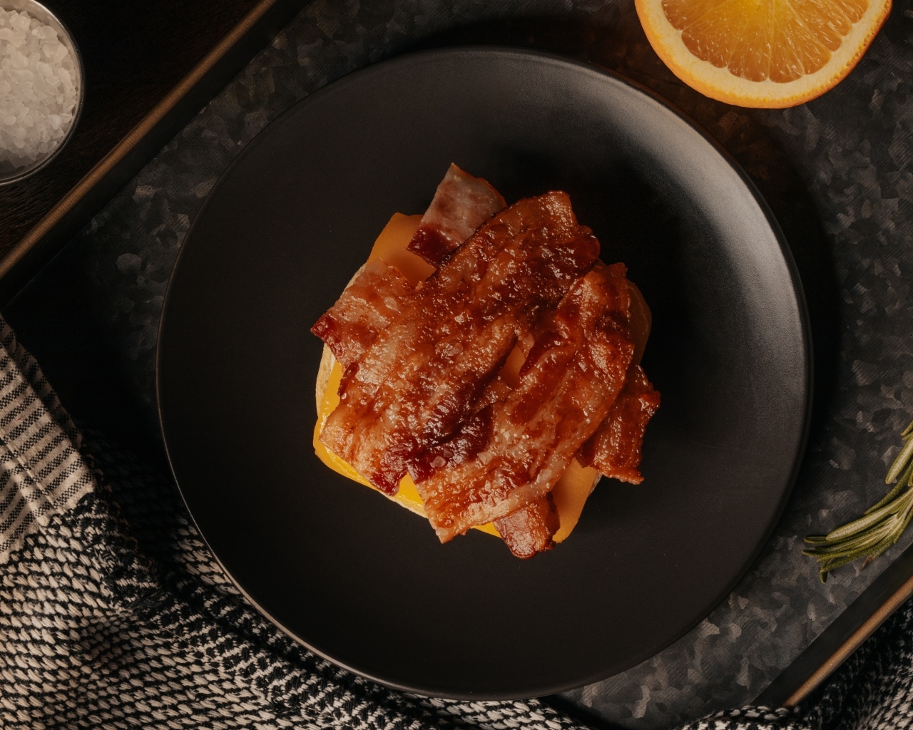 Бутерброд с сыром и жареным беконом на тарелке