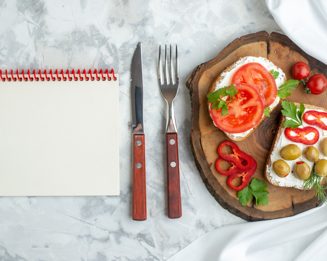 Бутерброды на столе со столовыми приборами и блокнотом