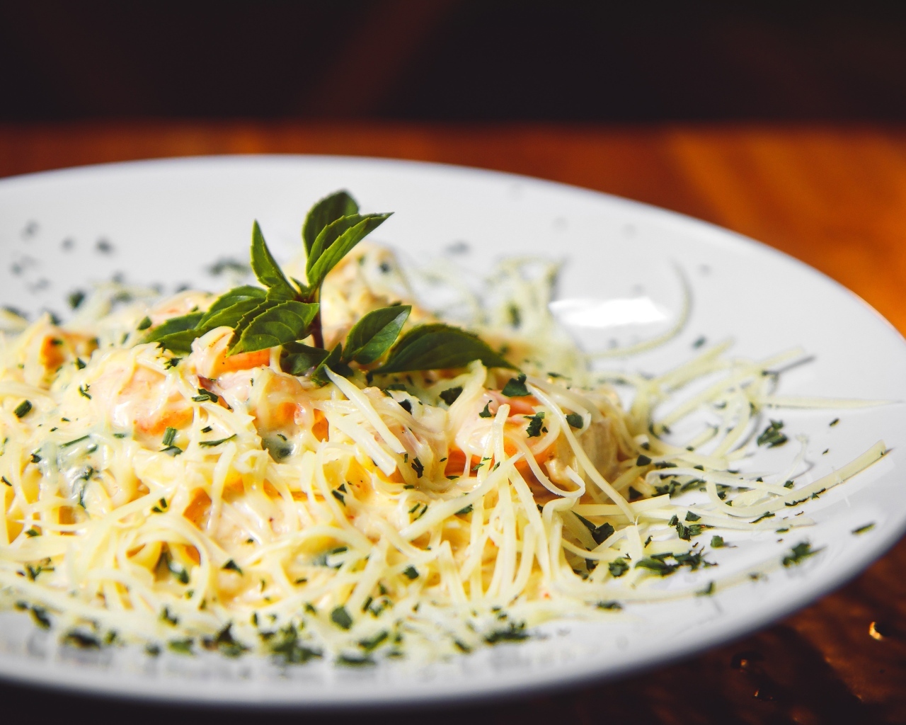 Спагетти с сыром и помидорами на белой тарелке