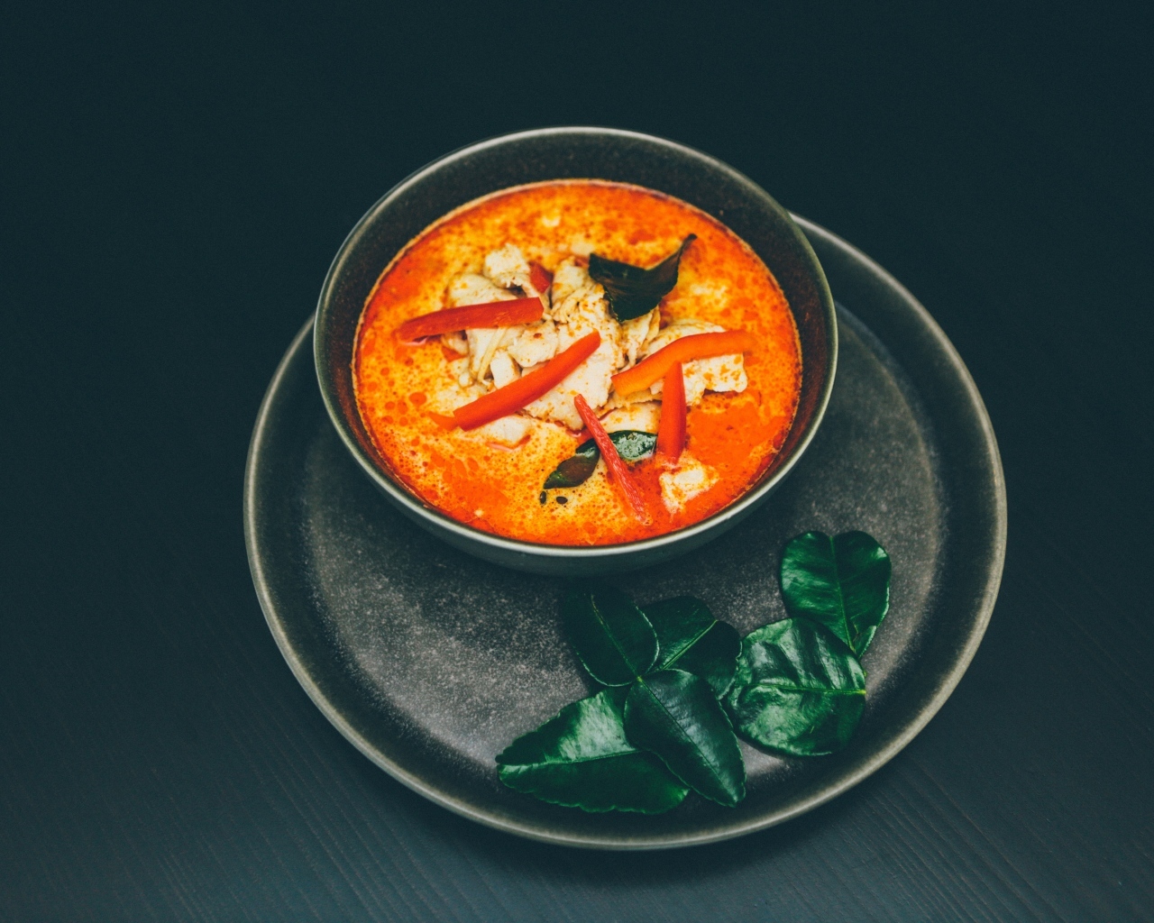 Острый суп в тарелке на черном фоне