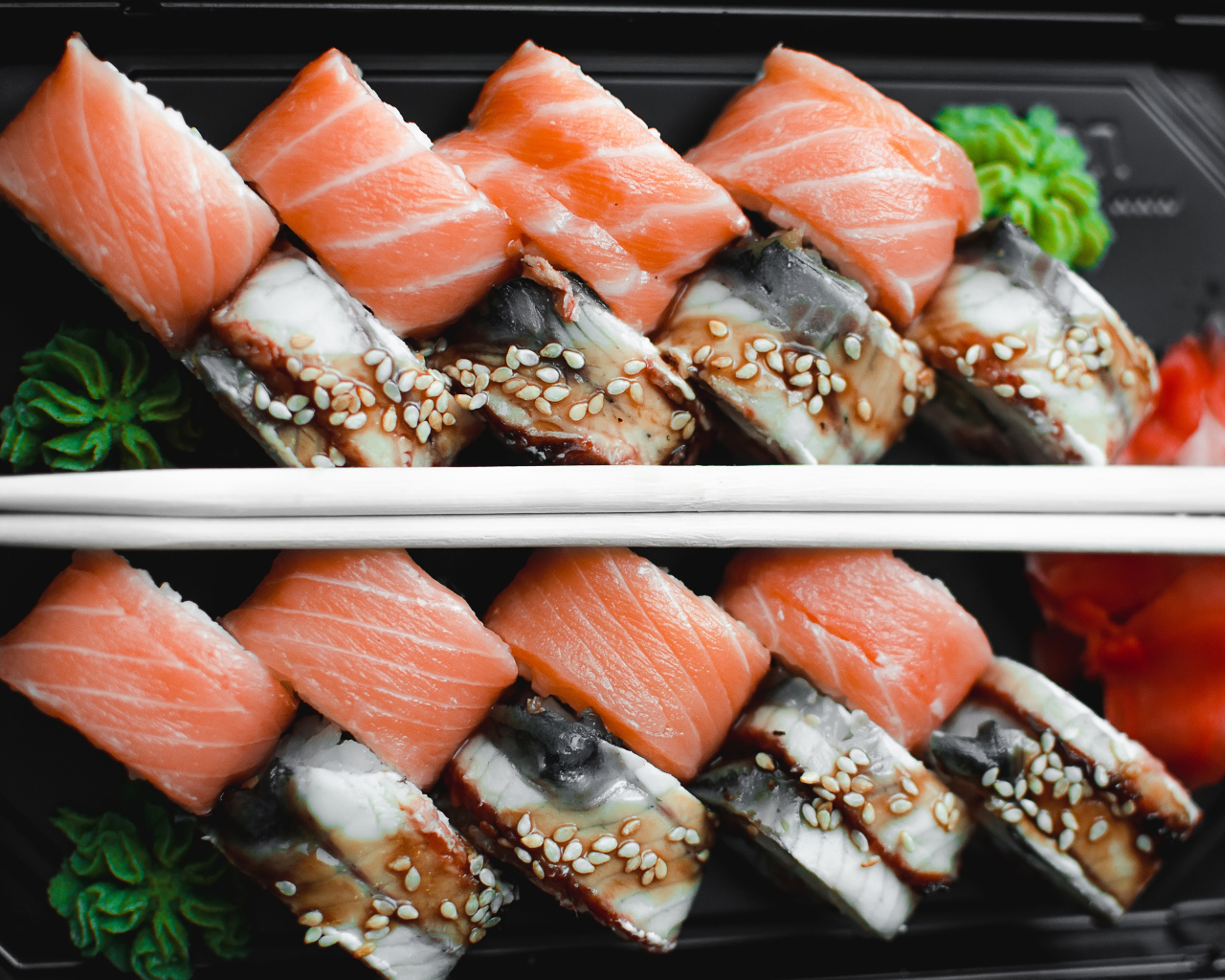 Суши с рыбой на черной тарелке с палочками