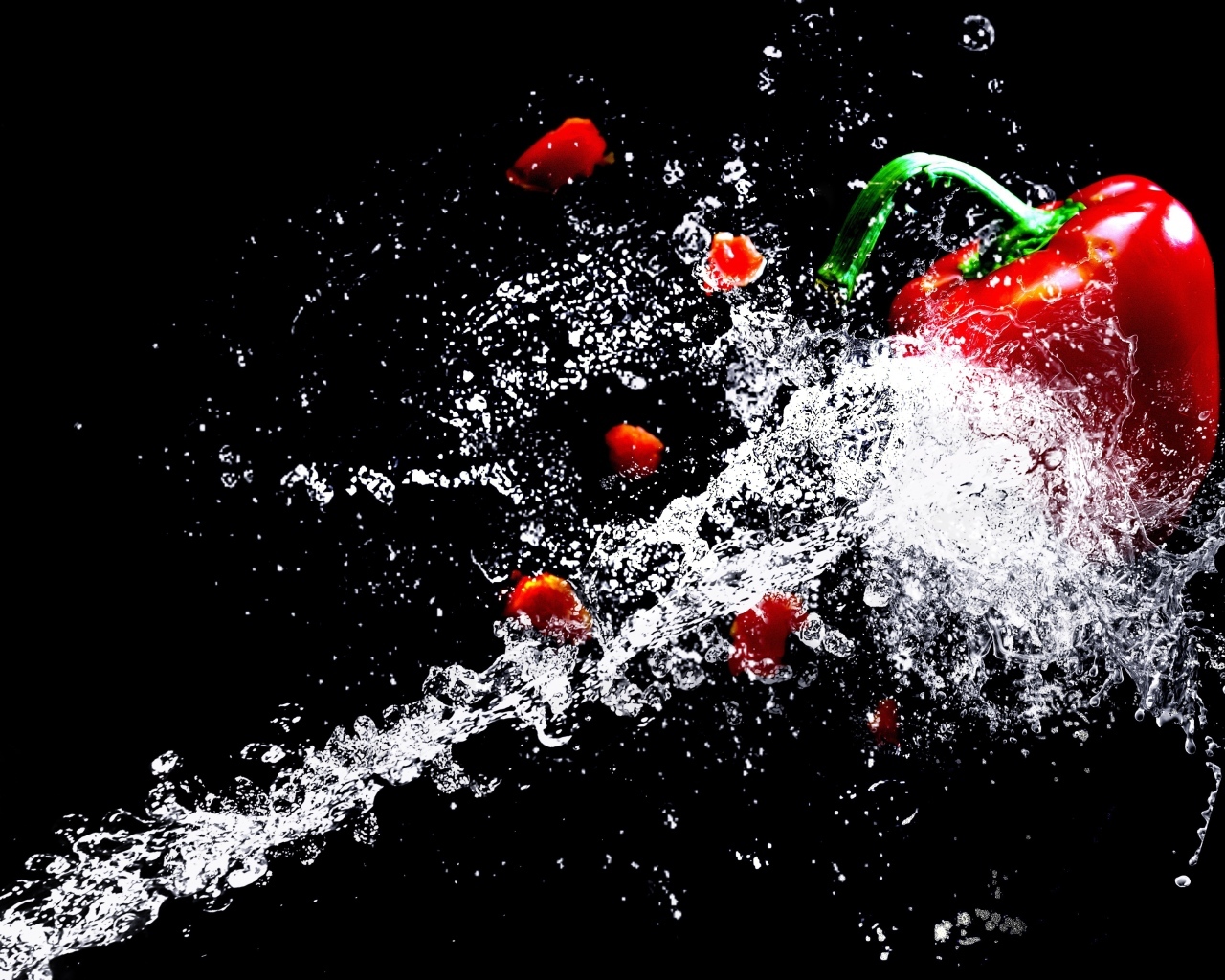 Сладкий красный перец в брызгах воды на черном фоне