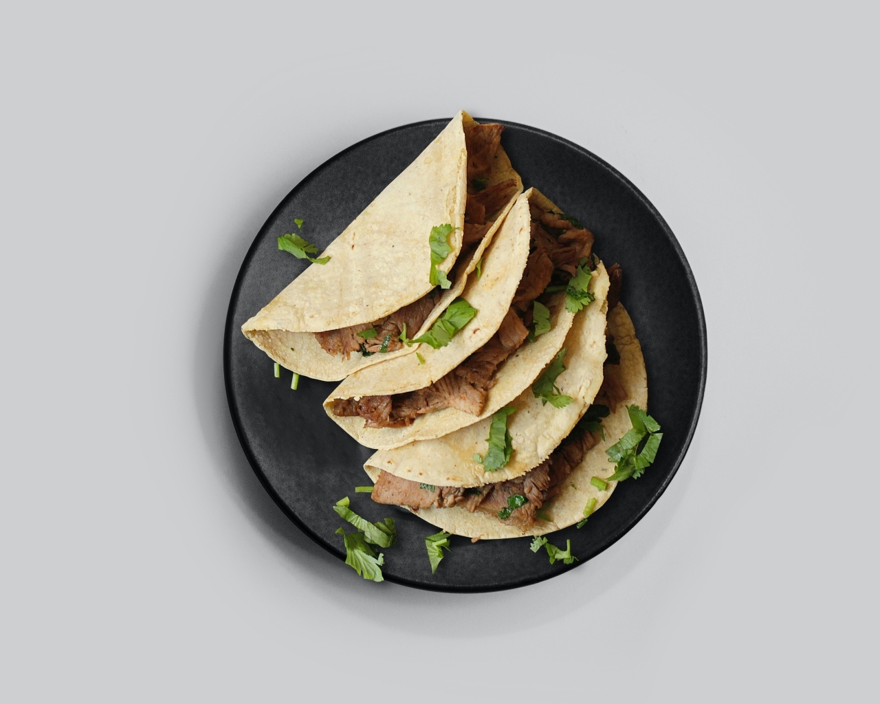 Блюдо тако в тарелке на сером фоне