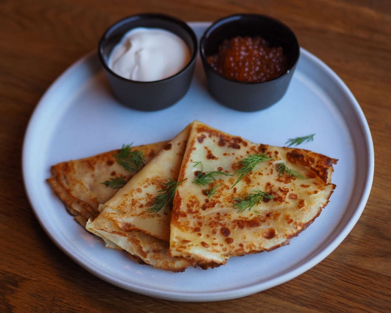 Тонкие блинчики на тарелке с красной икрой и сметаной