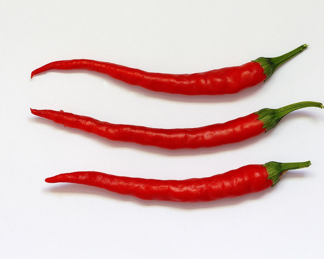 Три перца чили на сером фоне