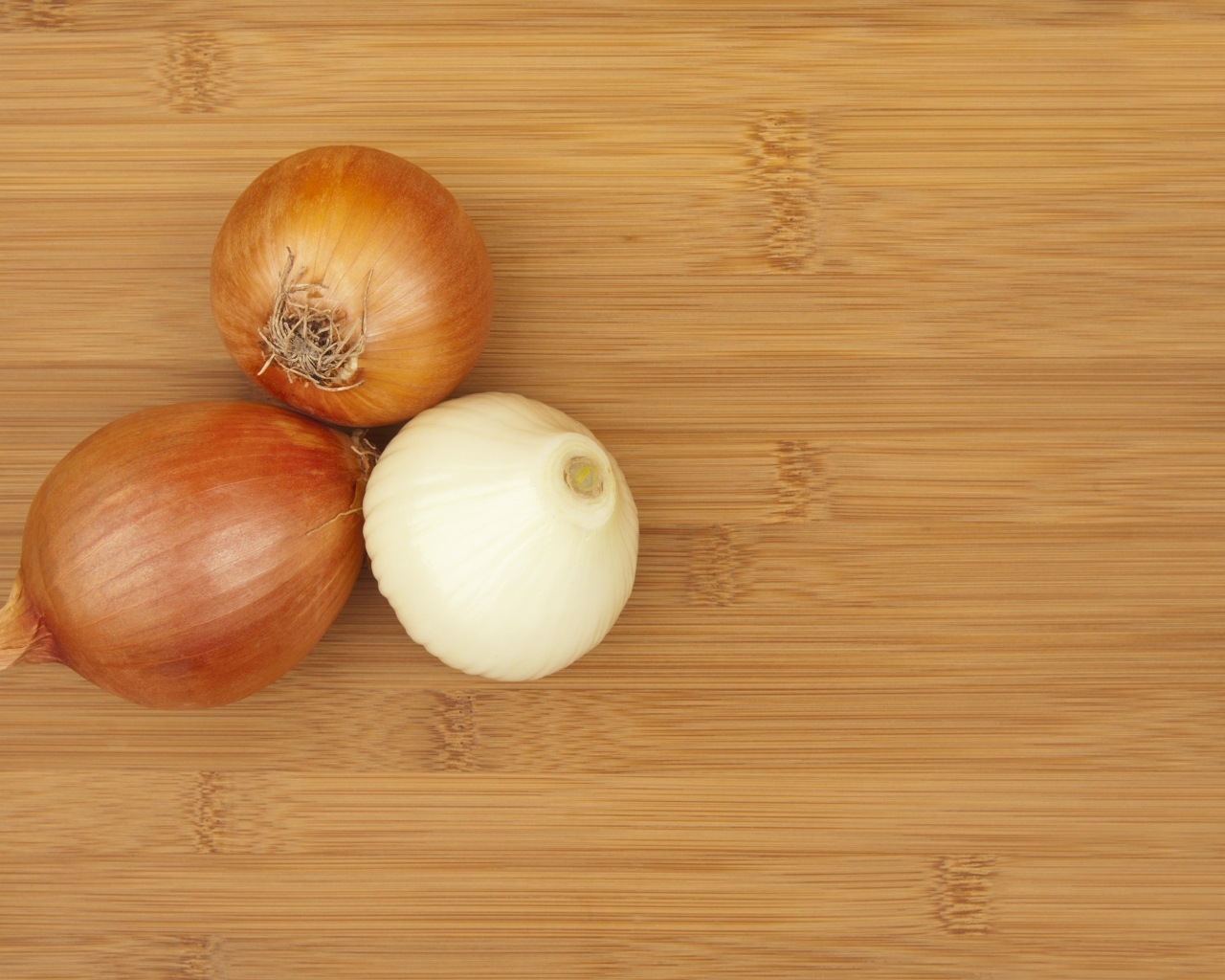 Три луковицы на деревянном столе