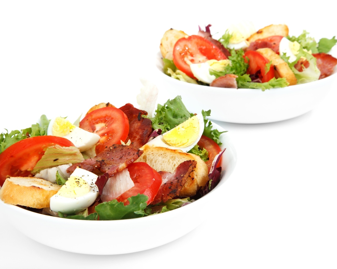 Две миски вкусного салата на белом фоне