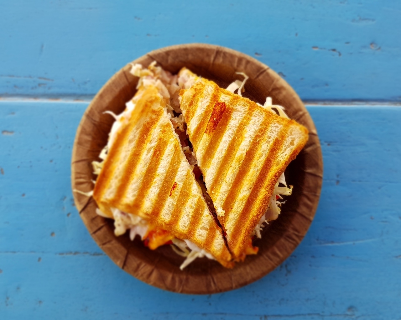 Два сэндвича на тарелке на голубом столе