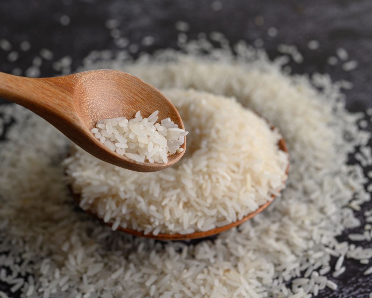 Белый рис на столе с деревянной ложкой 