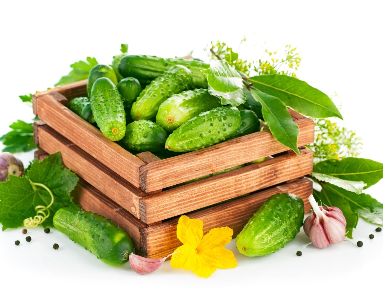 Деревянный ящик с зелеными огурцами и пряностями