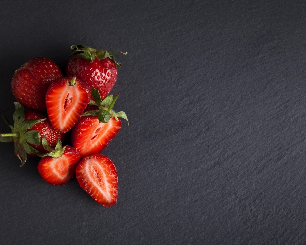 Горсть спелой клубники на сером столе