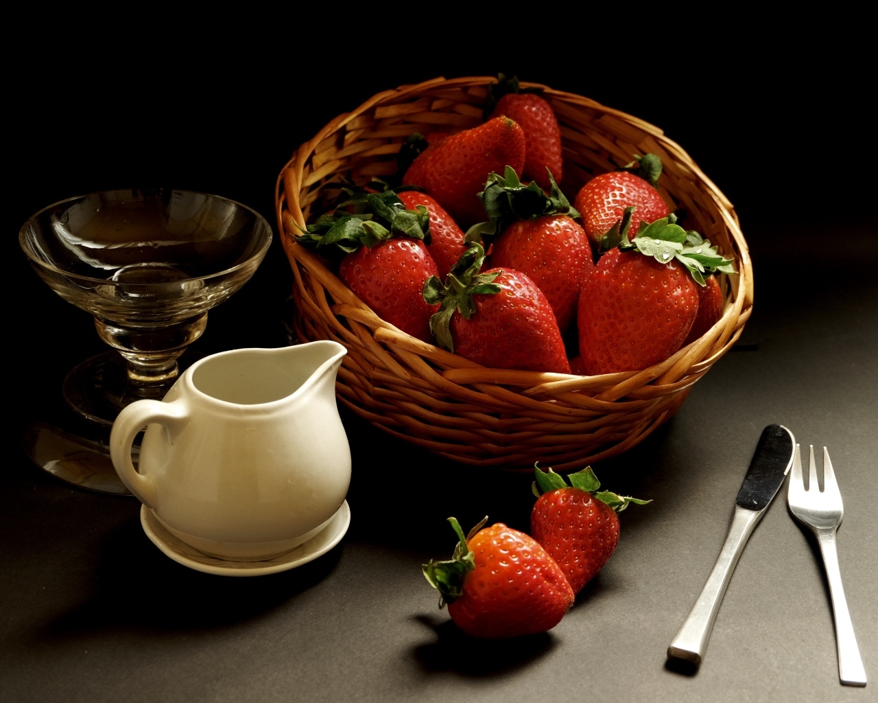 Корзина со спелой красной клубникой на столе с посудой