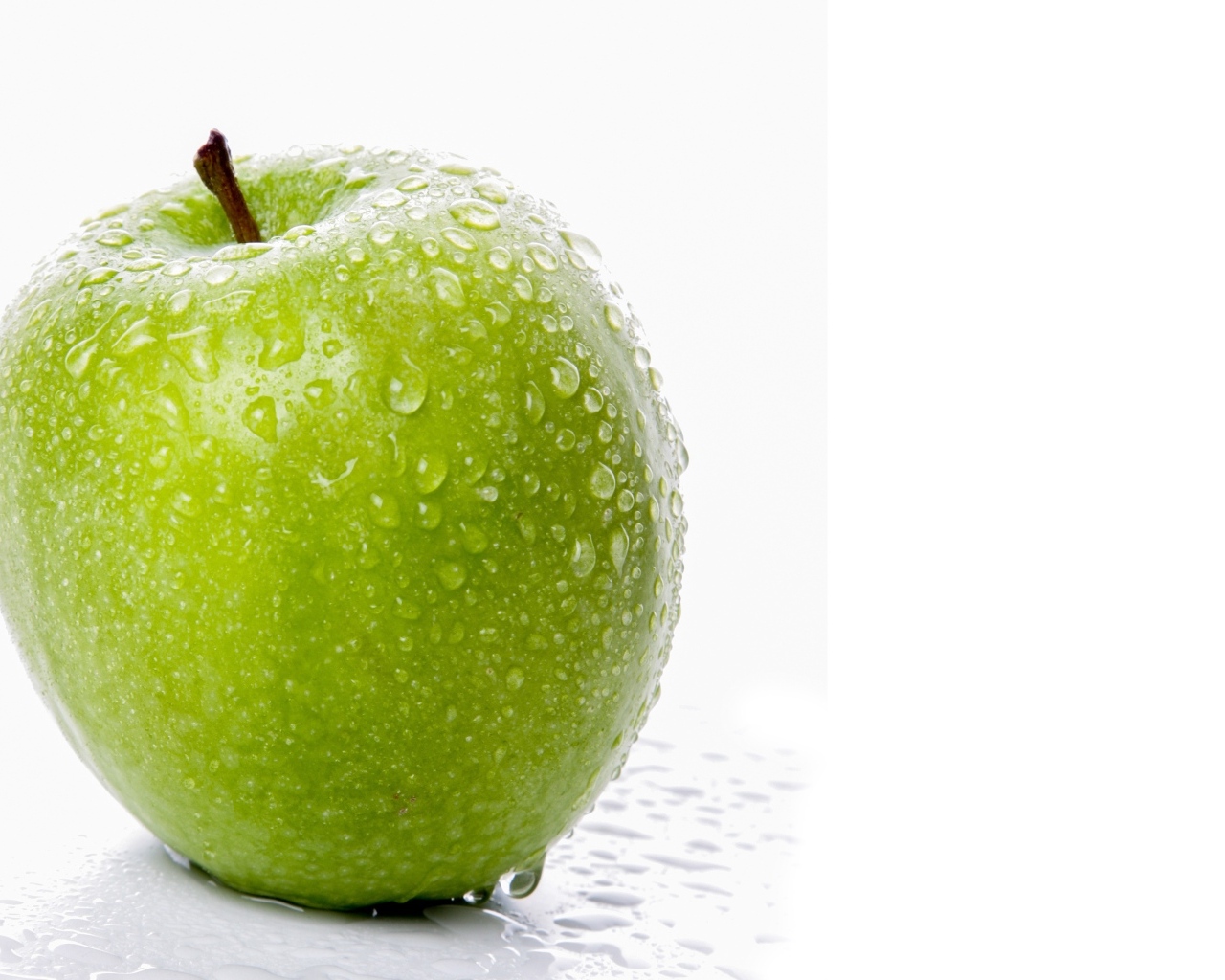 Большое зеленое яблоко в каплях воды на белом фоне