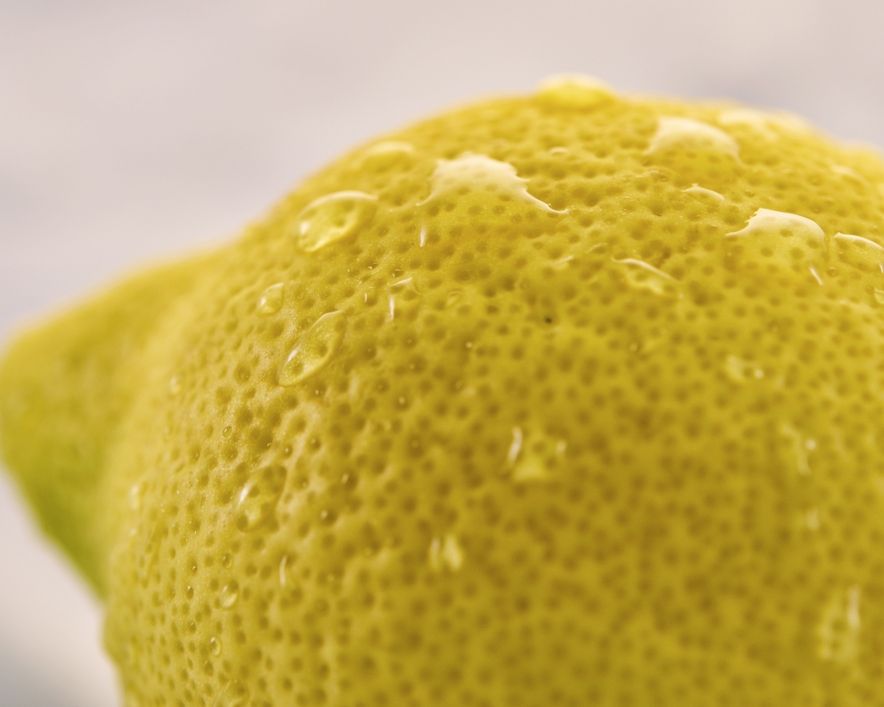 Большой желтый лимон в каплях воды крупным планом