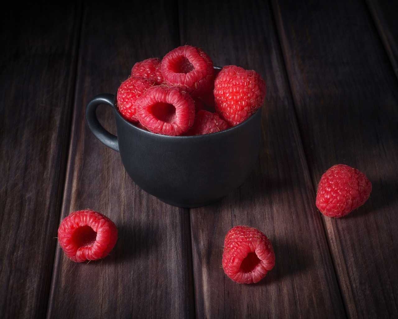 Черная чашка с красными ягодами малины