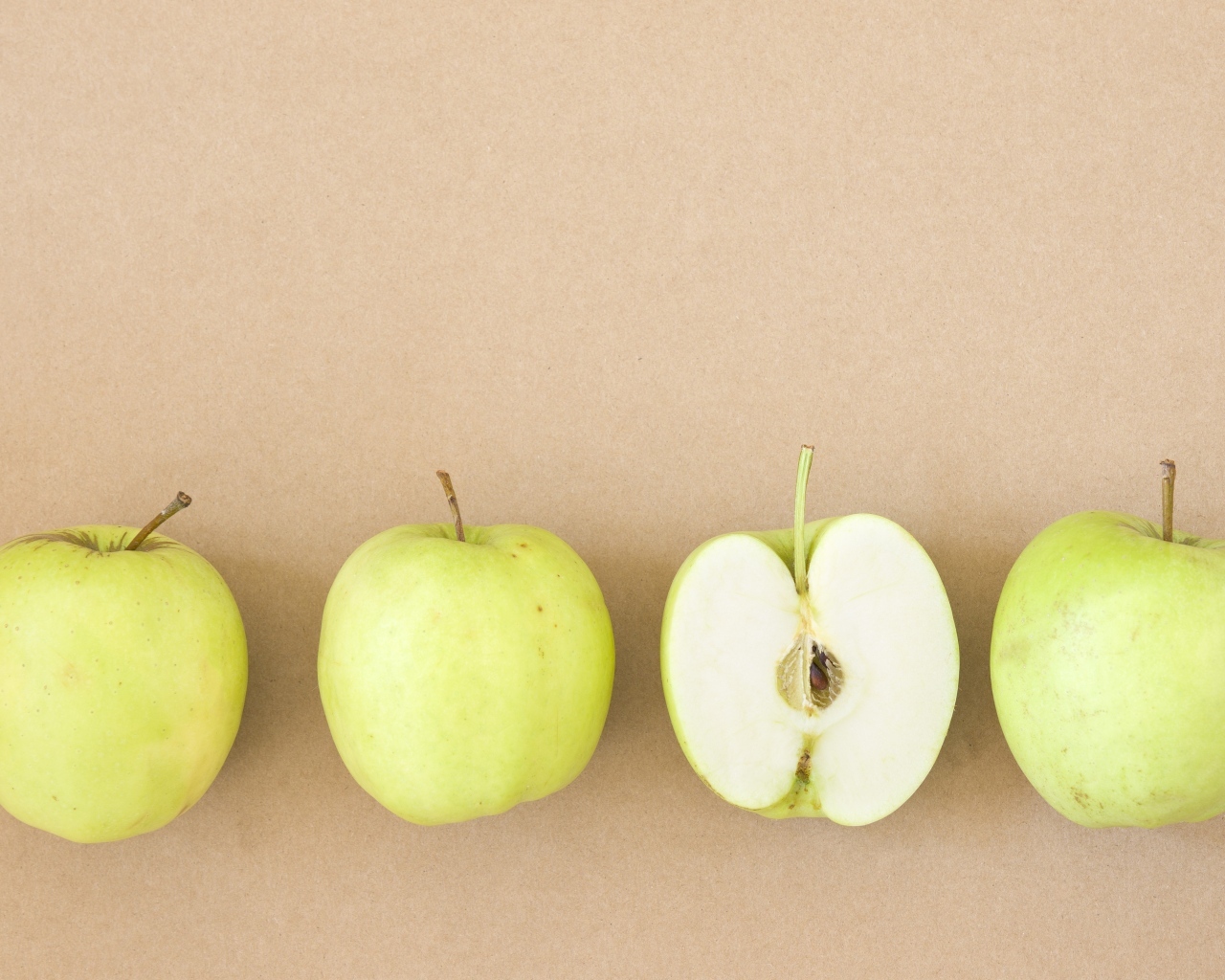 Четыре зеленых яблока на бежевом фоне 
