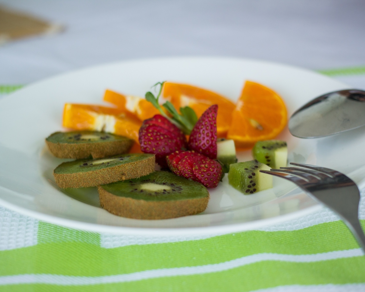 Свежие нарезанные фрукты на тарелке с вилкой