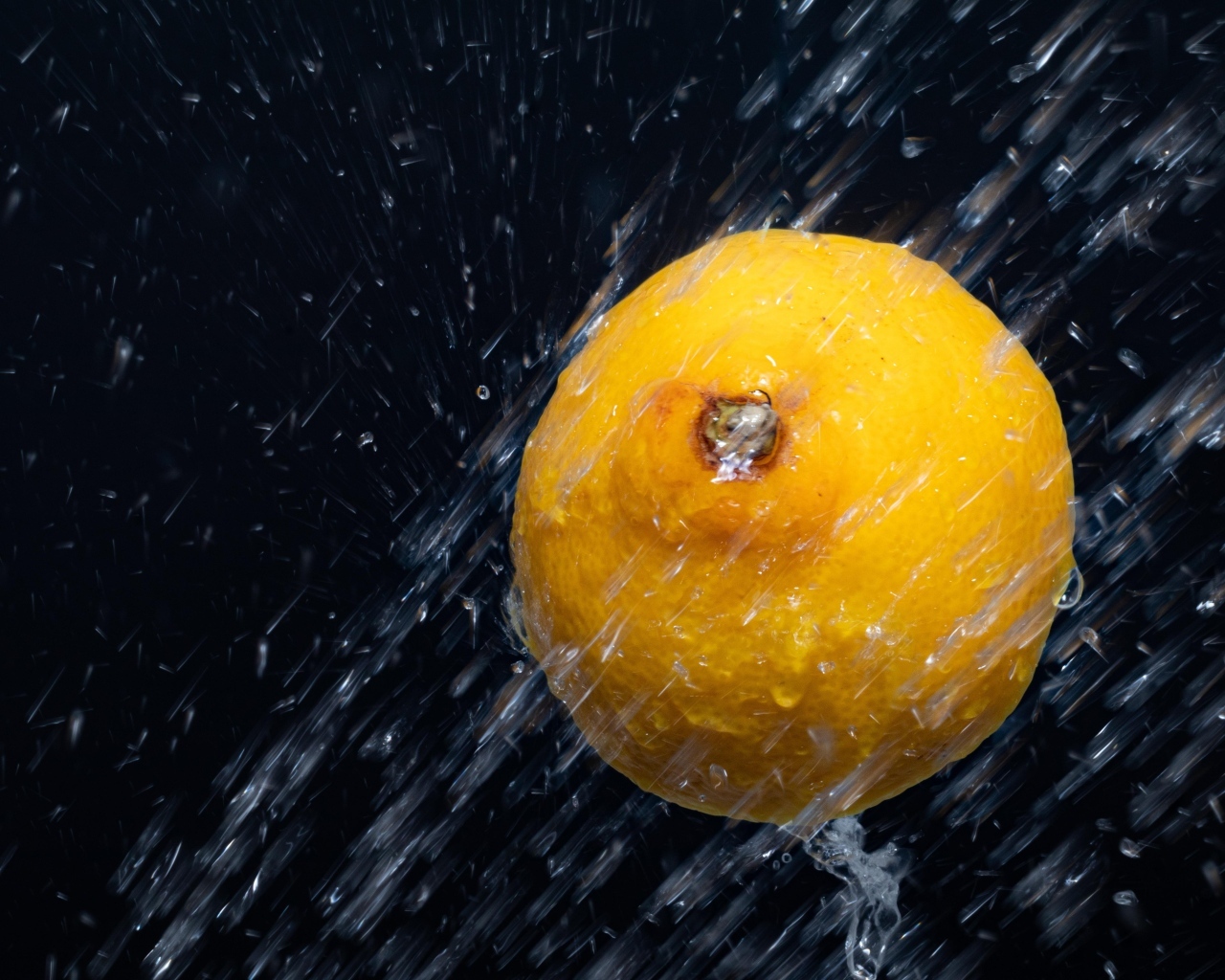 Лимон в брызгах воды на черном фоне