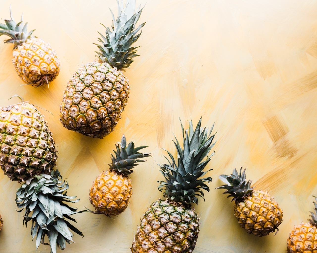 Много ананасов на желтом фоне