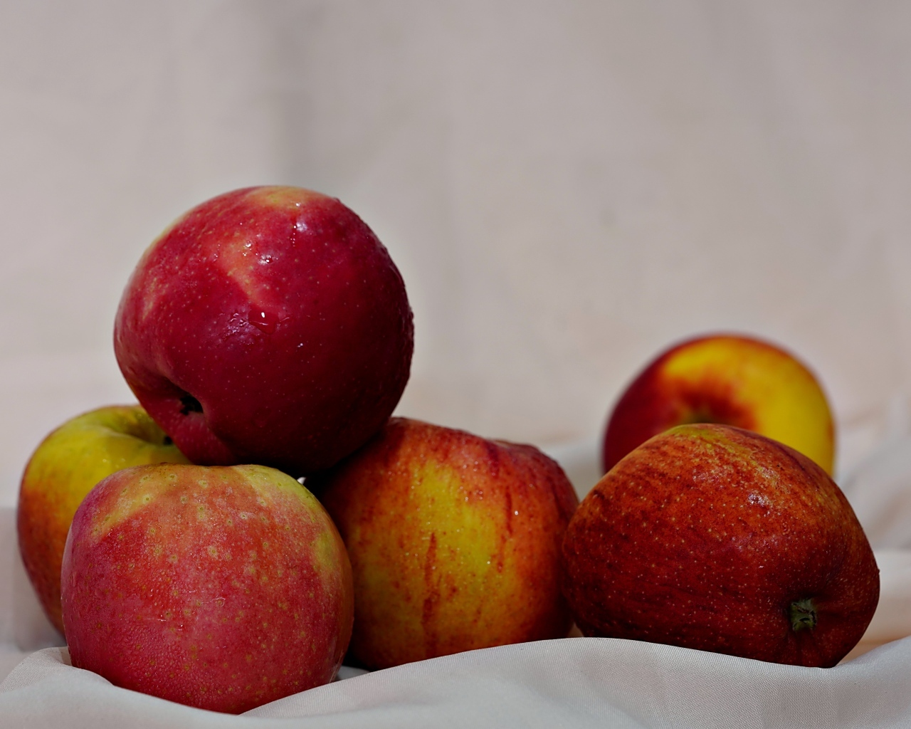 Много красных яблок с белой тканью 