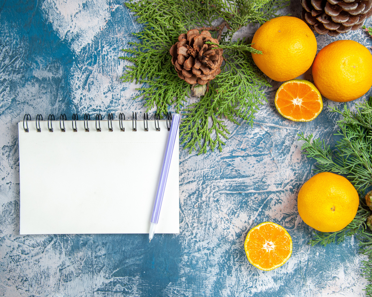 Блокнот на столе с мандаринами и ветками
