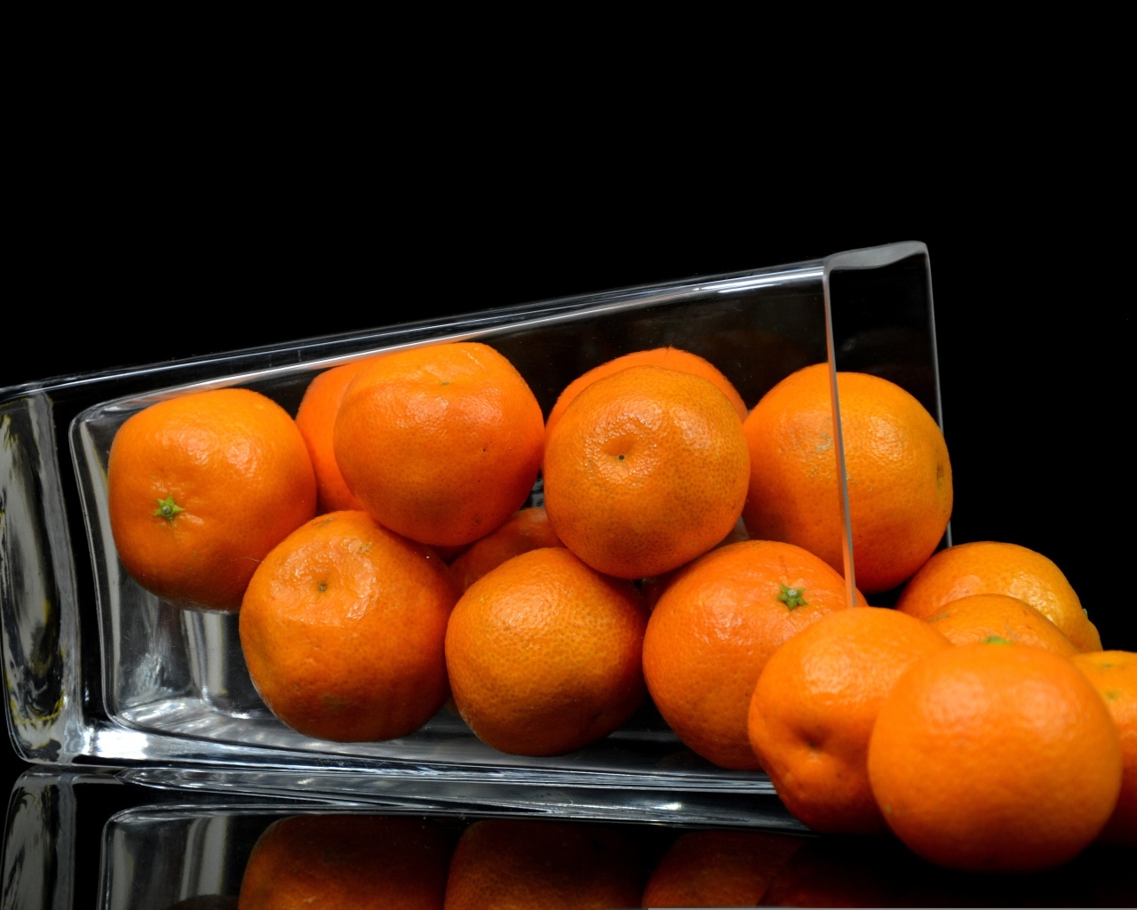 Оранжевые мандарины в стакане на черном фоне