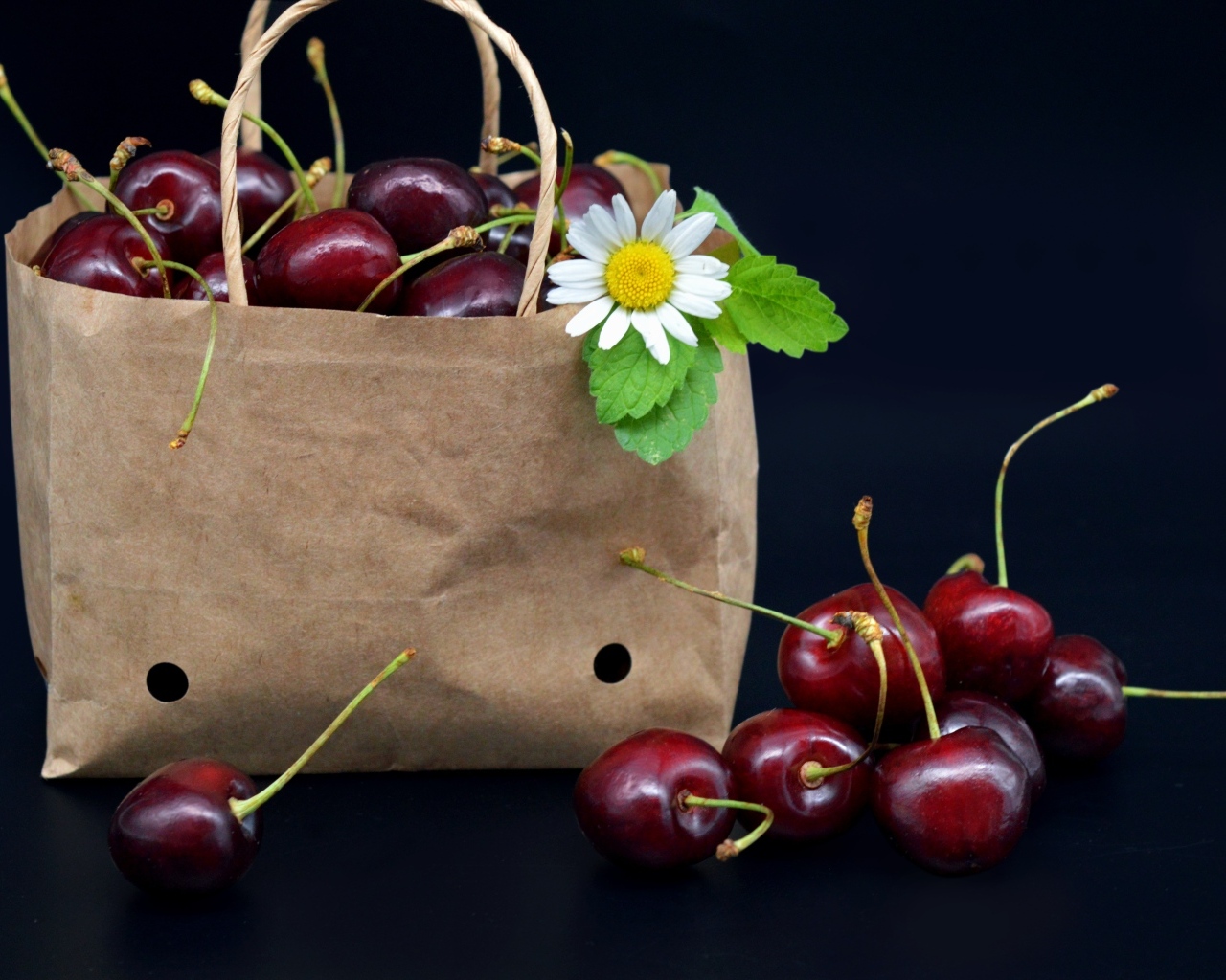 Бумажный пакет с ягодами черешни на черном фоне